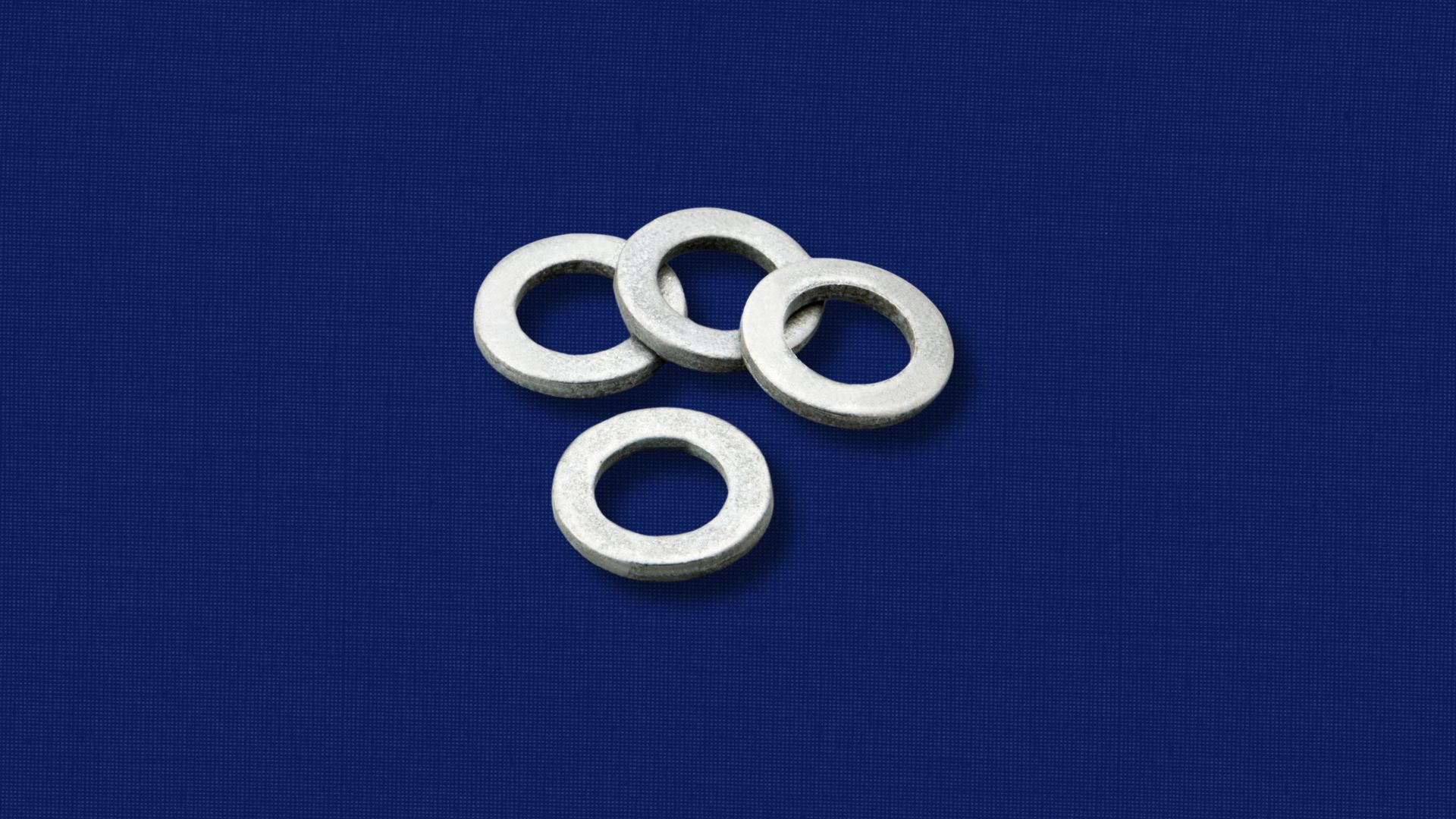 Three washers are sitting on top of each other on a blue surface.