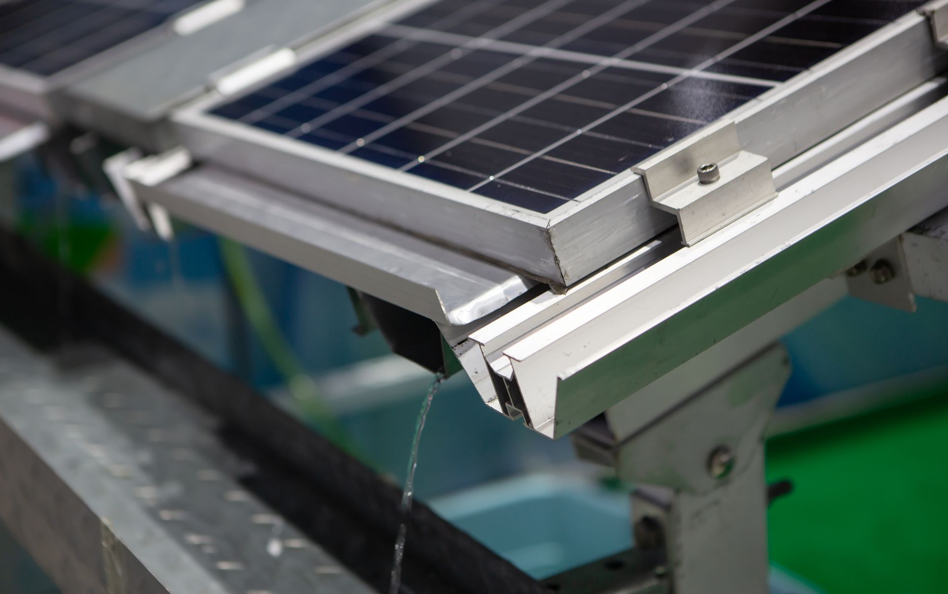 Close-up of solar panels with aluminum framing and water dripping from the edge.