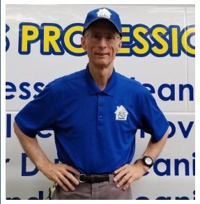 Man in blue uniform and cap with logo, hands on hips, standing in front of a service van. Man in blue uniform and cap with logo, hands on hips, standing in front of a service van.