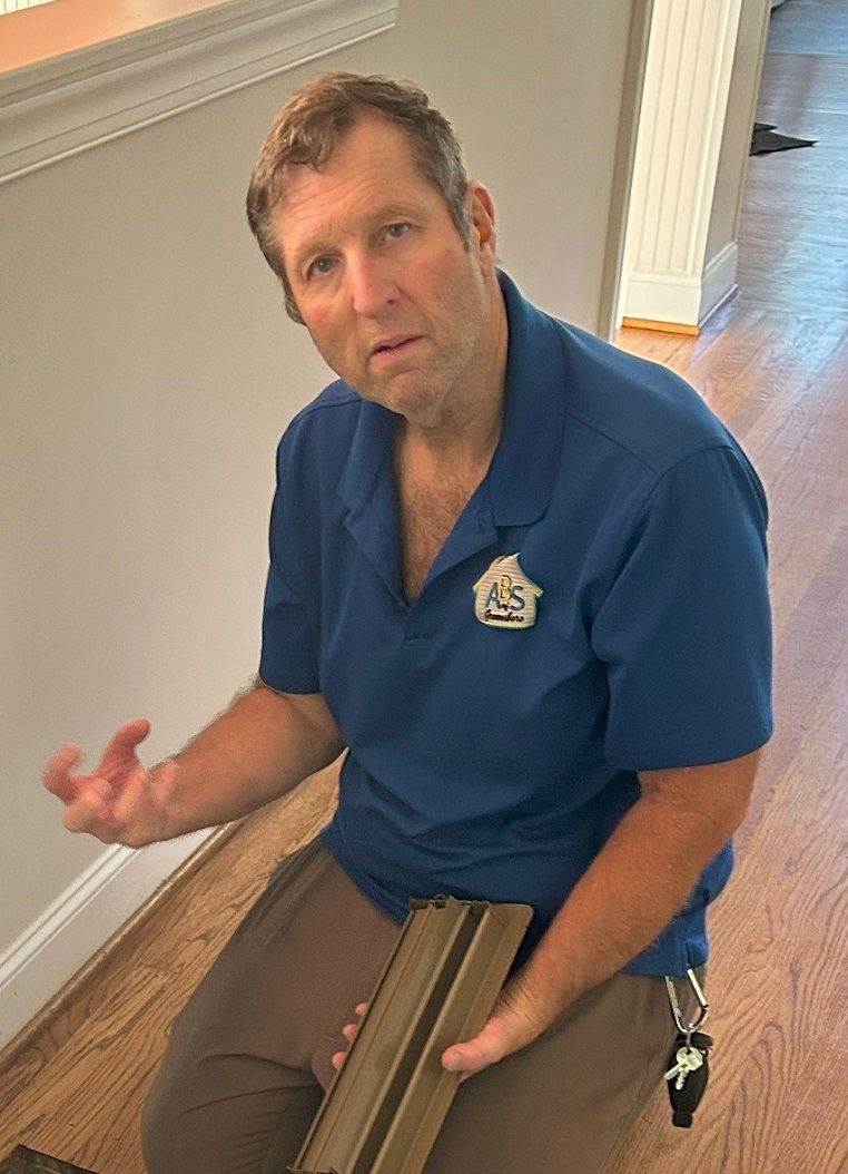 Man in blue shirt, holding wood trim, looking up with a confused expression. Indoors, wooden floor. Man in blue shirt, holding wood trim, looking up with a confused expression. Indoors, wooden floor.