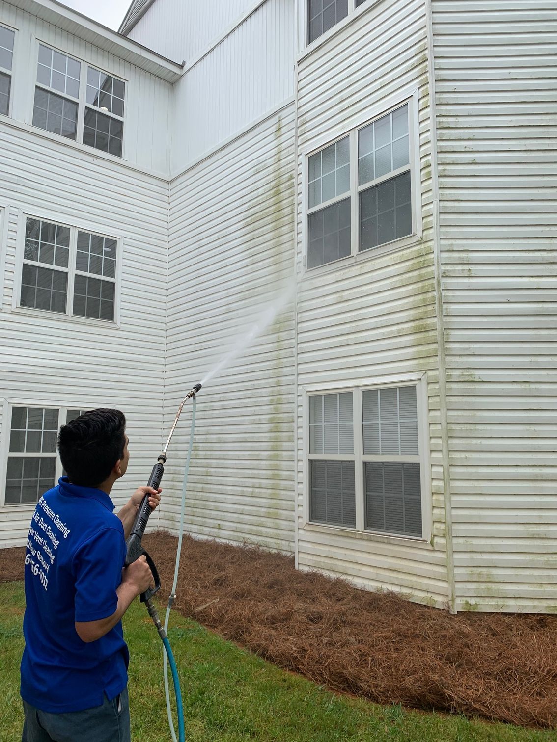 Window being cleaned with a long-handled squeegee, against a white-framed window on a brick building.