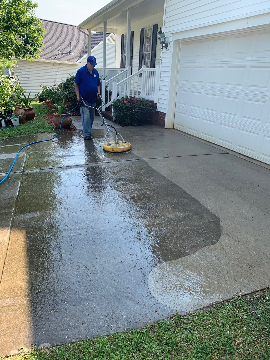 Person in boots power washing a wooden deck with a high-pressure washer.