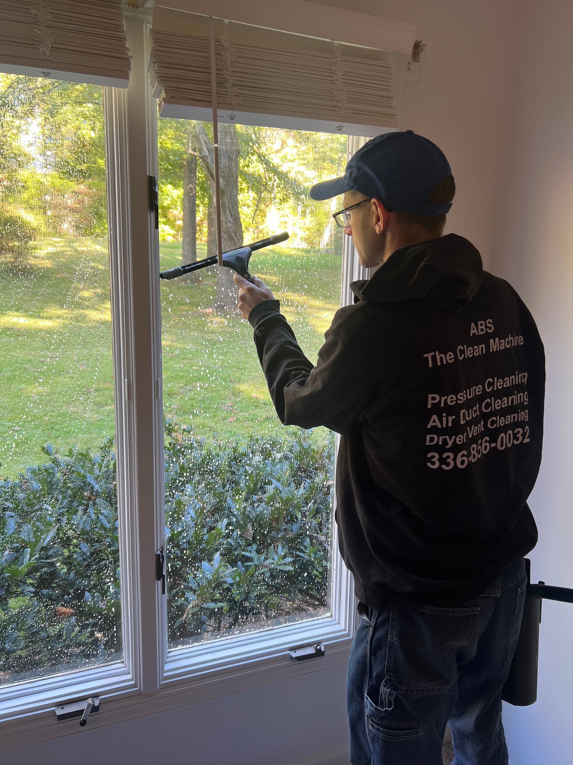 Cleaning supplies, green bucket with spray bottles, mop, sponges, and gloves on a wood floor.