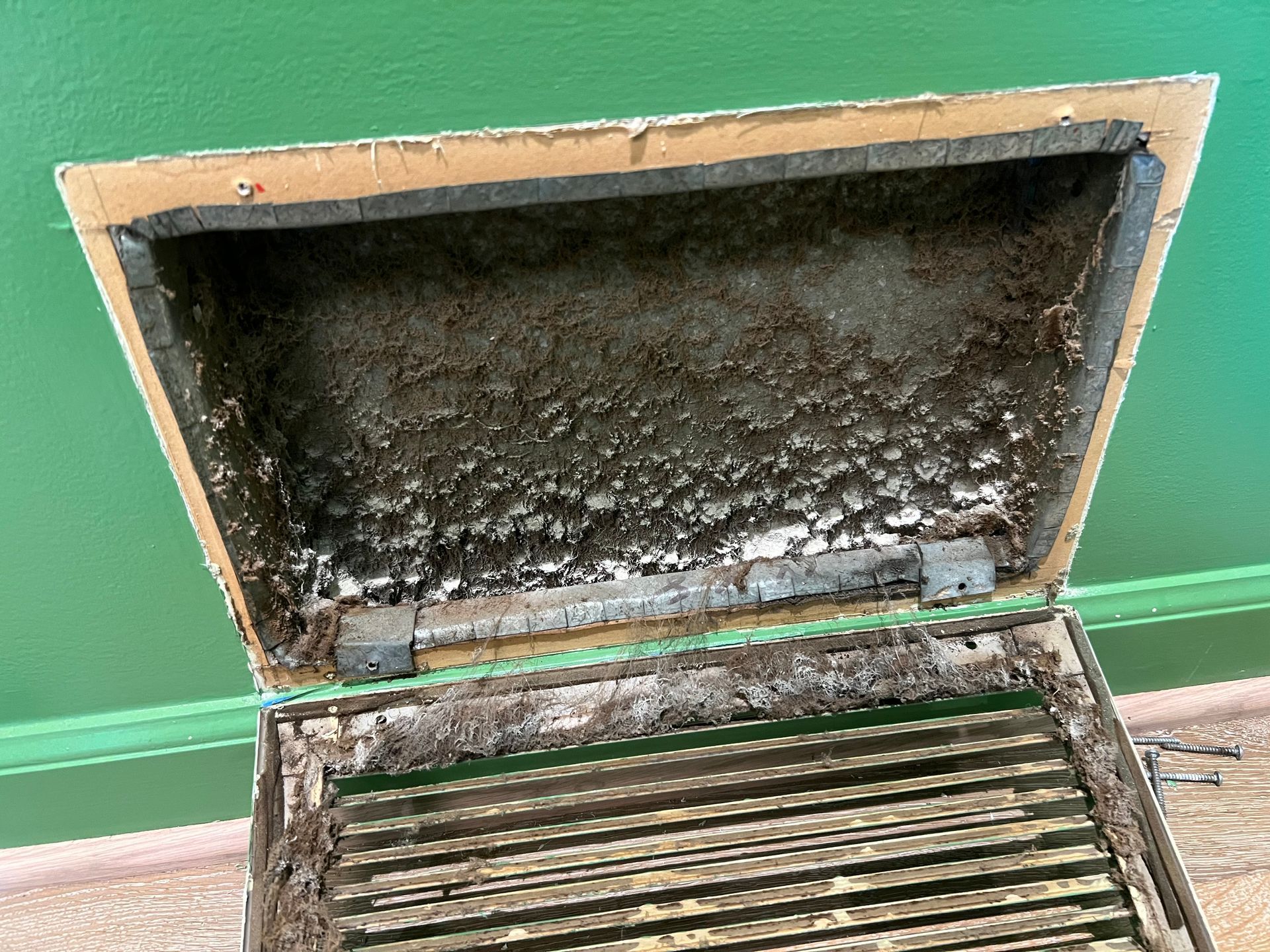 Man cleaning air duct with rotating brush.