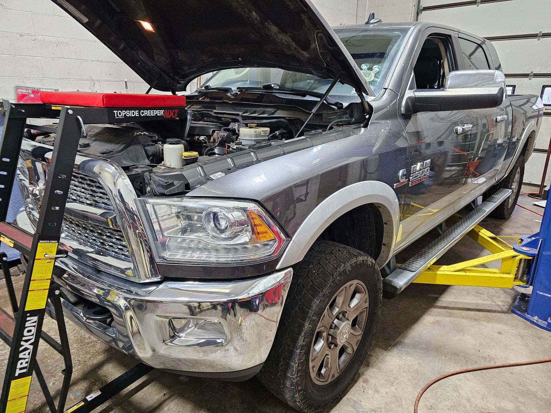 Gray pickup truck with hood up, on a lift, in a shop. | Black River Automotive