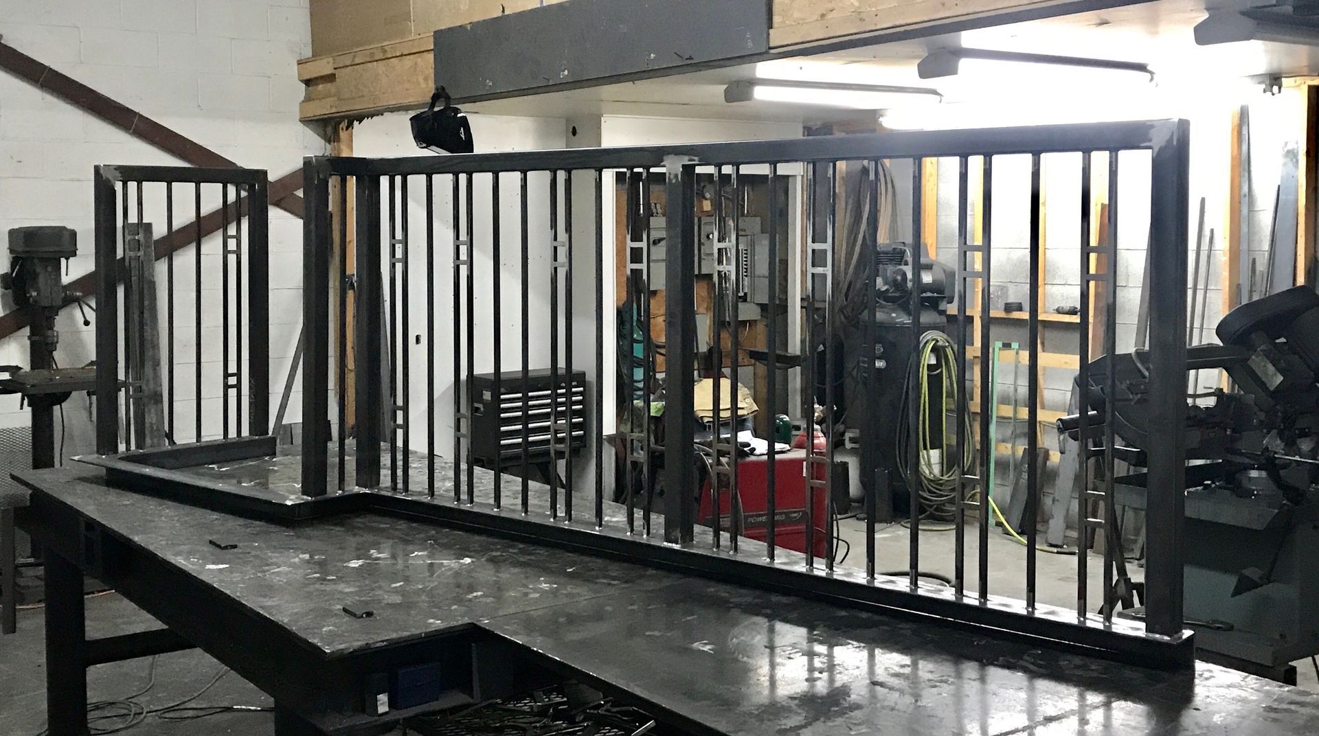 Éléments de rambarde en métal noir sur un établi dans un atelier.