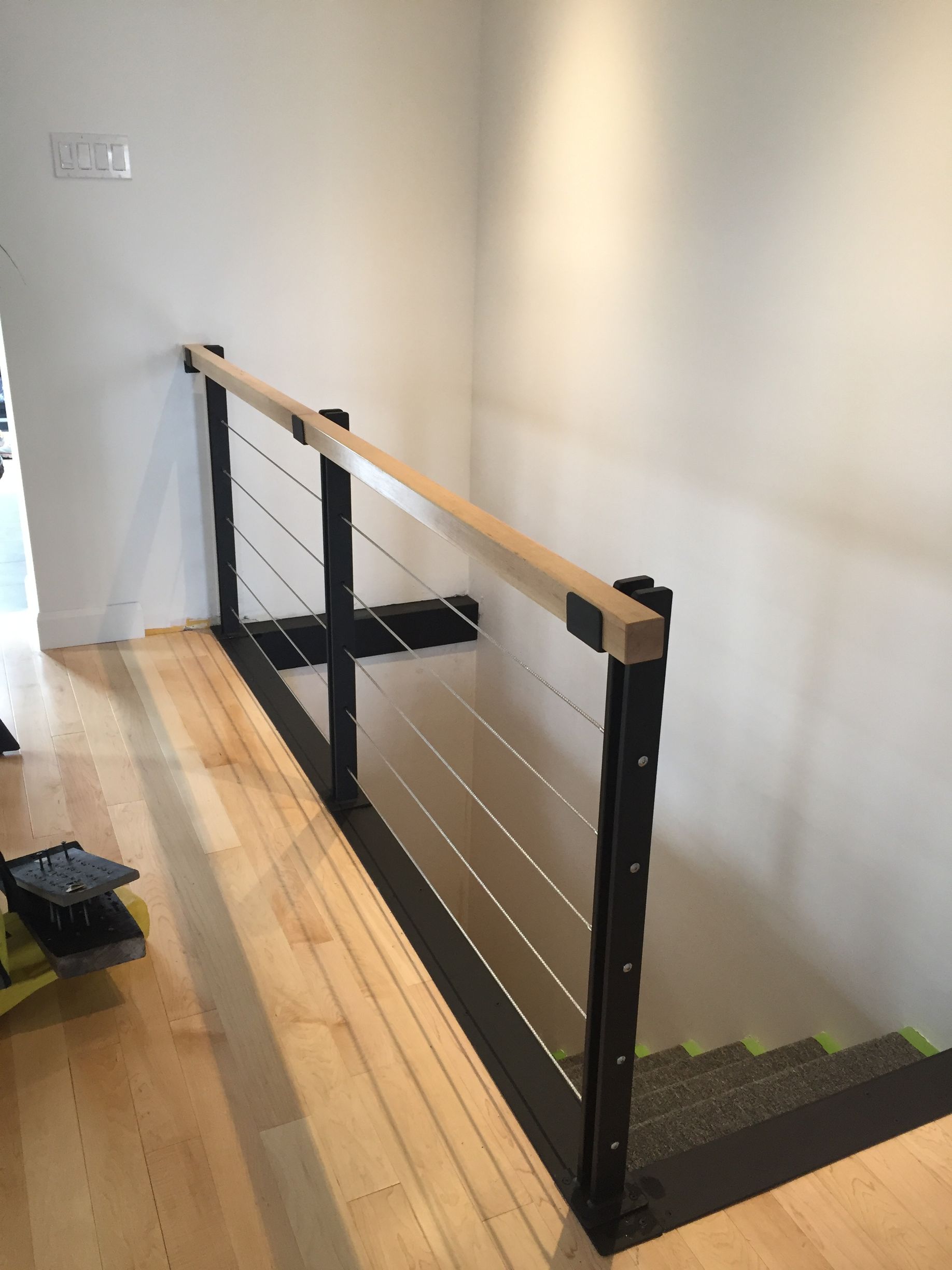 Rambarde d'escalier moderne avec remplissage par câbles et main courante en bois dans un couloir.