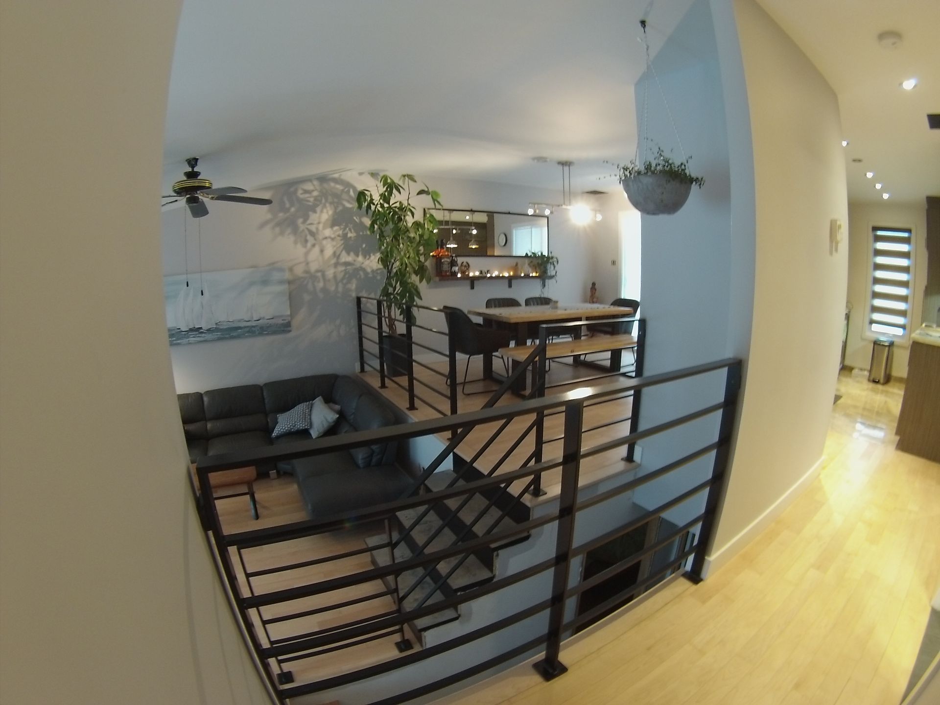 Vue intérieure d'une maison moderne avec un escalier, un salon et un espace repas.