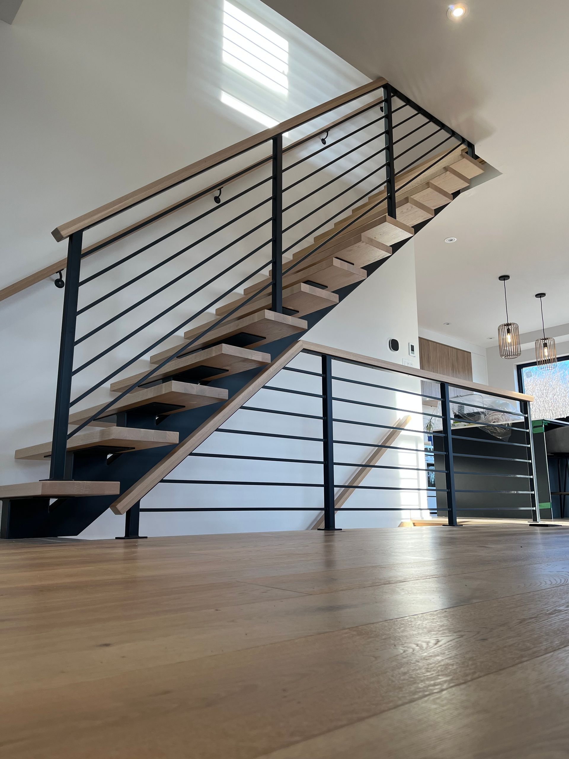 Escalier en bois avec rampes en métal noir dans une maison moderne.