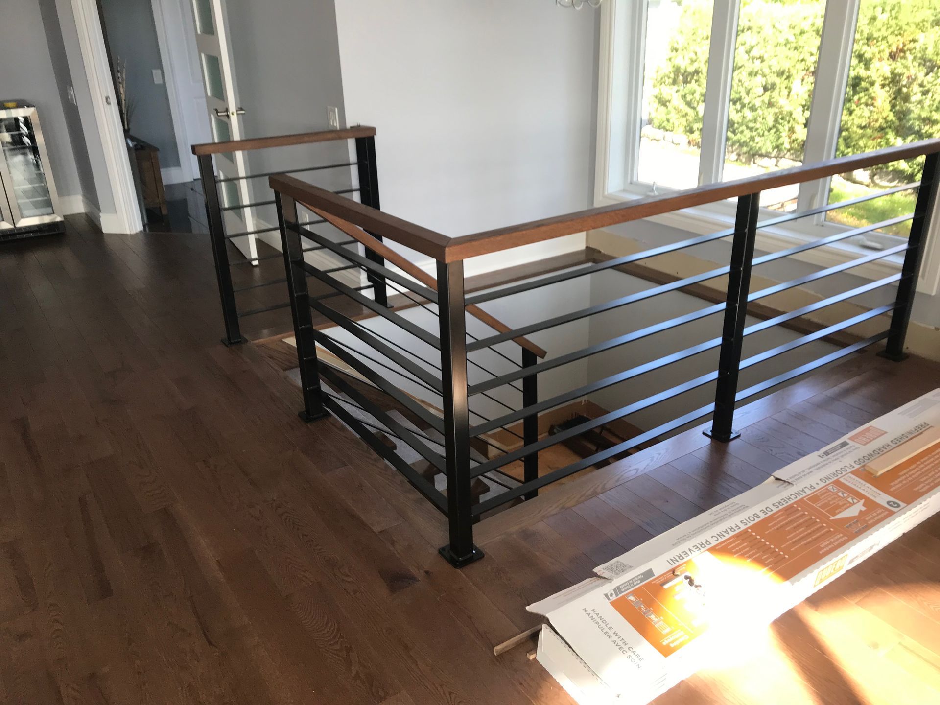 Escalier moderne avec rampes en bois et barres en métal noir.