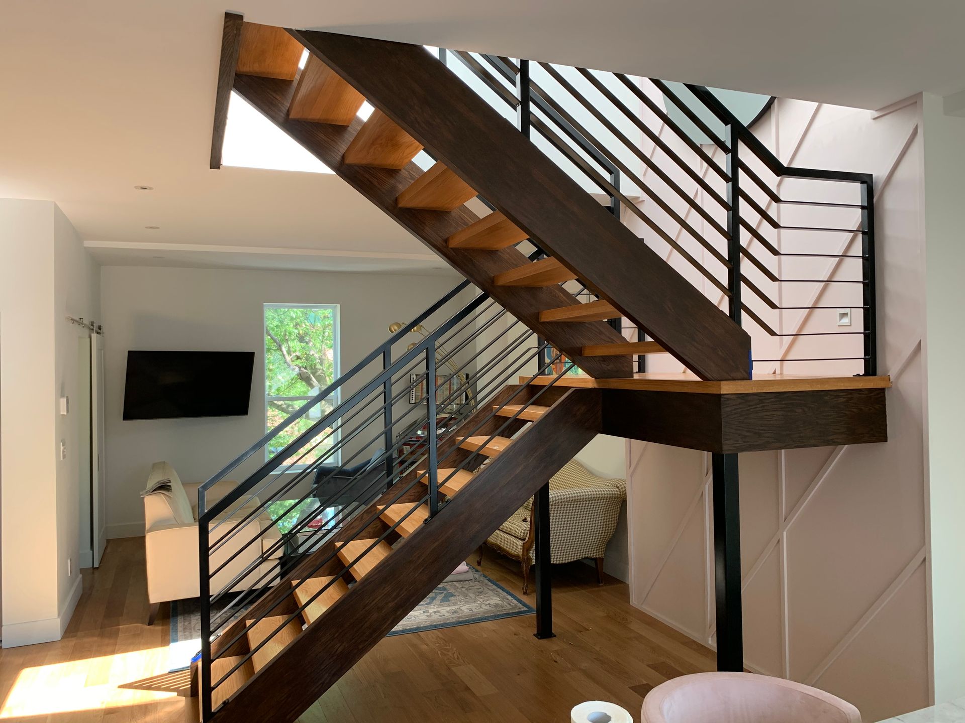 Escalier en bois avec rampes en métal noir dans une maison moderne.