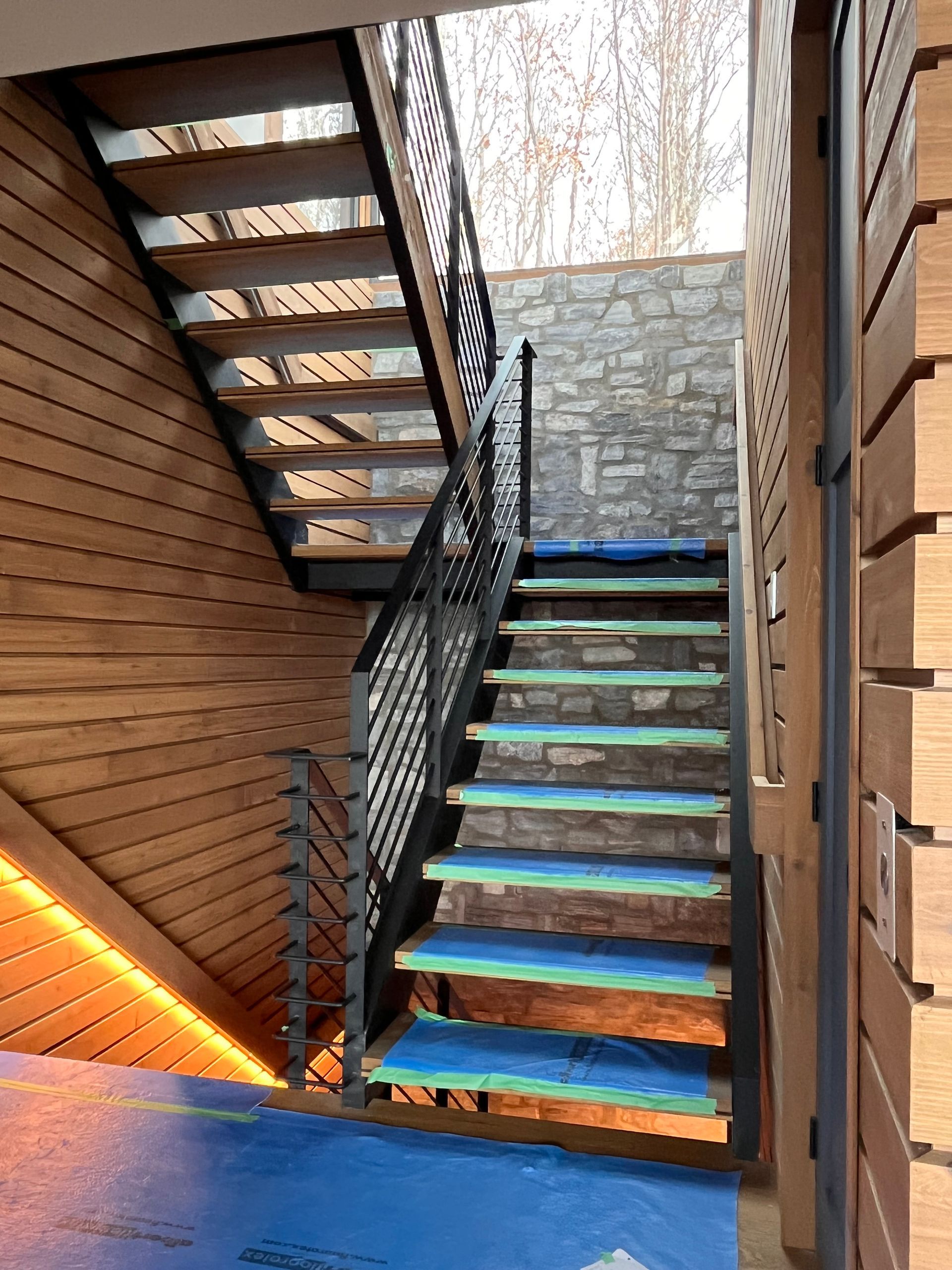 Un escalier en bois et métal mène à l'étage supérieur. Les marches sont protégées par une bâche bleue.