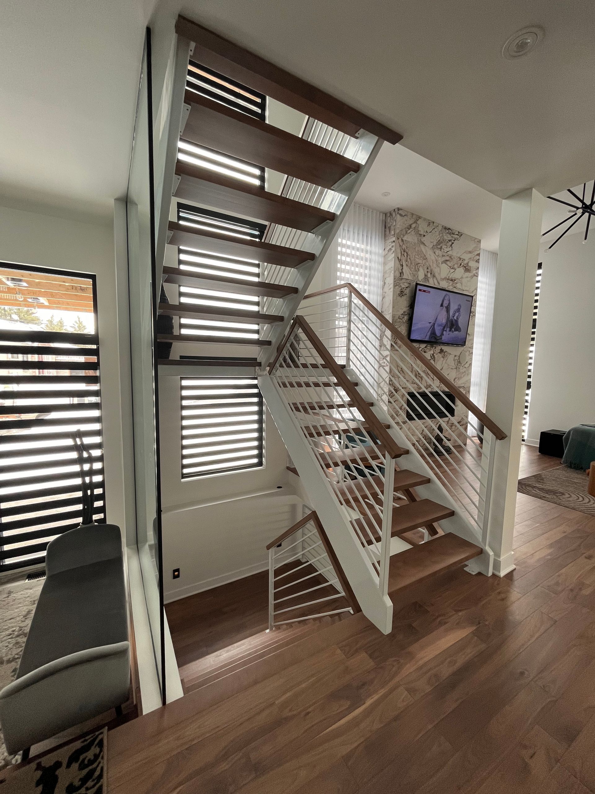 Escalier en bois avec rampes blanches, câbles en acier et plancher en bois.