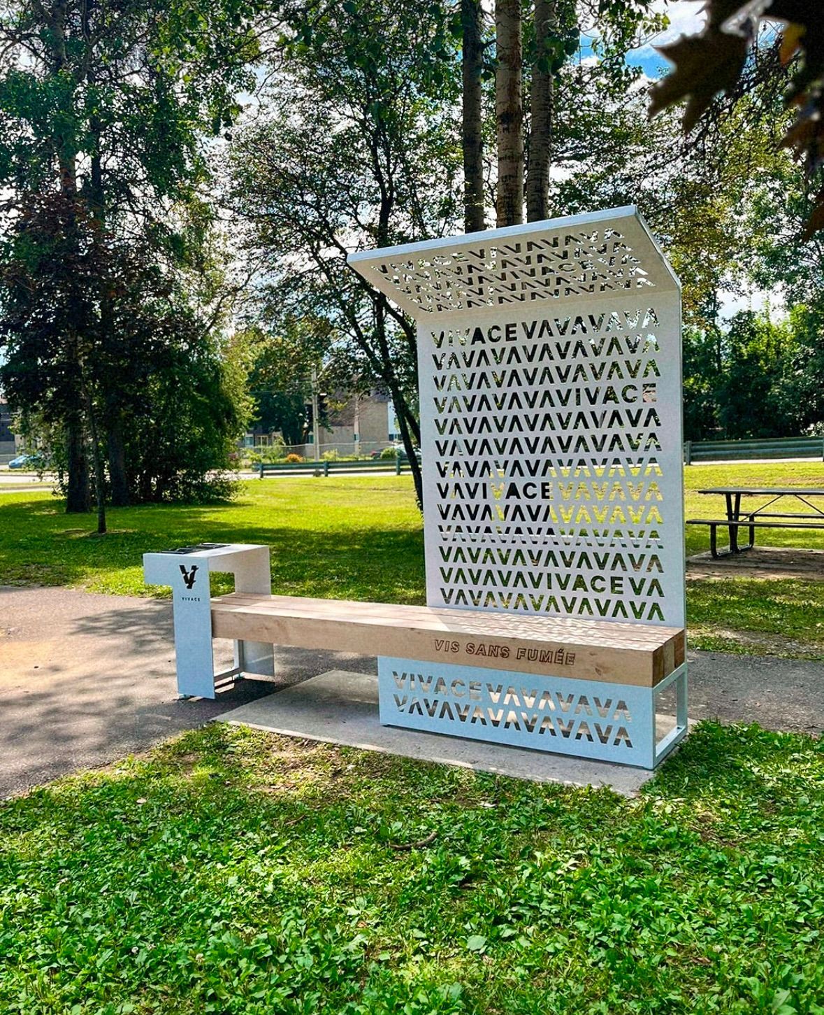 Banc blanc avec dossier décoratif et panneau supérieur, dans un parc.