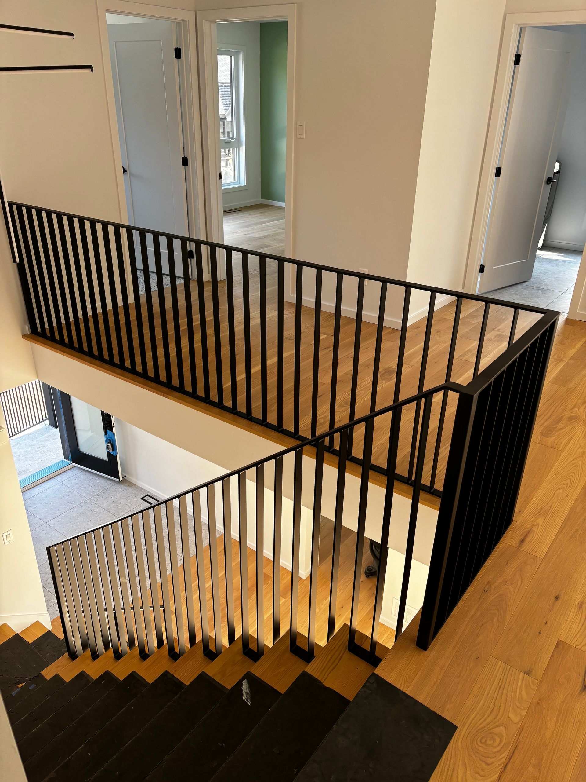 Escalier avec rampe en métal noir. Parquet et marches en bois clair. Vue intérieure d'une maison.