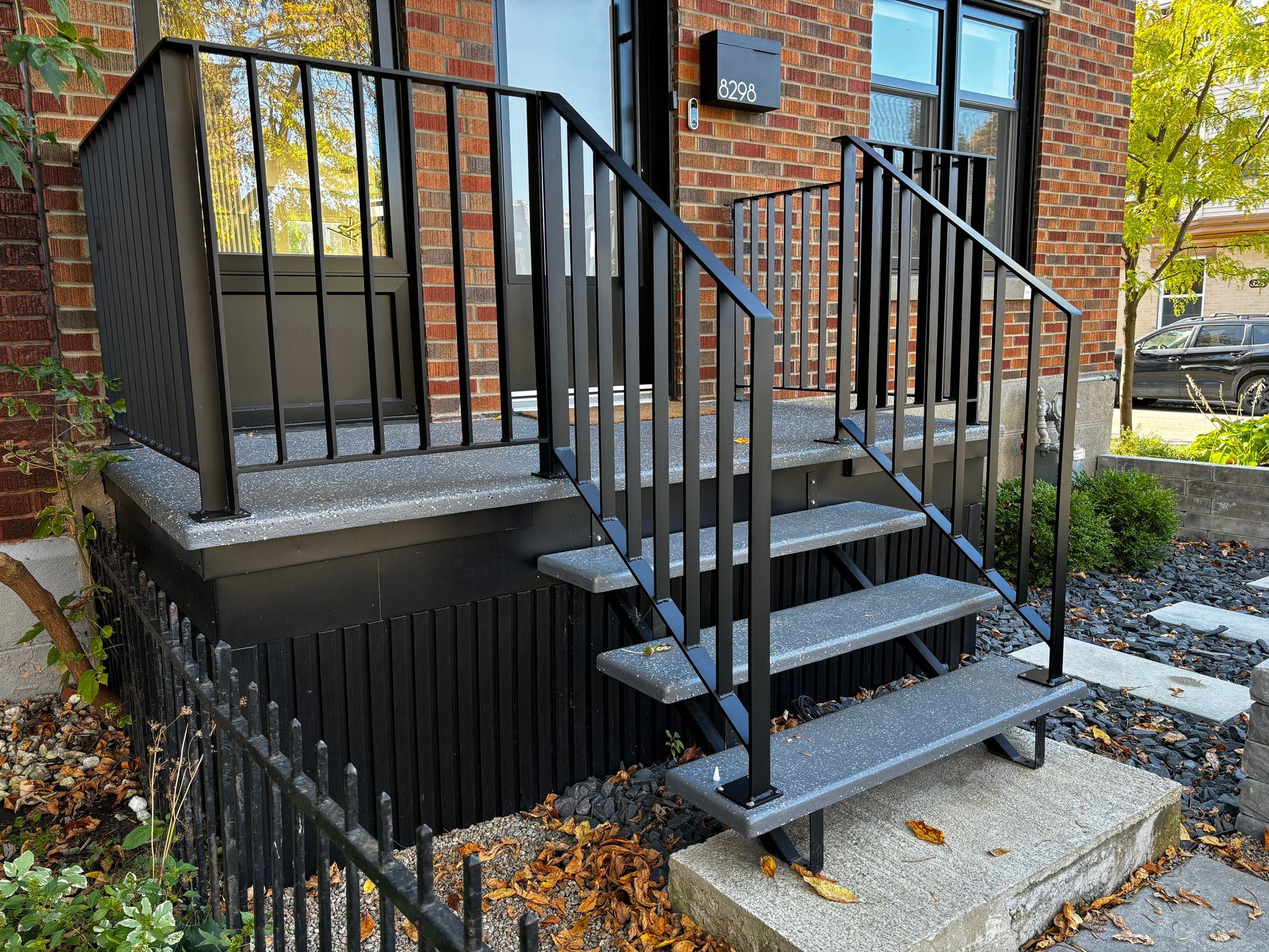 Rambardes et escaliers en métal noir menant à l'entrée d'un bâtiment en briques.