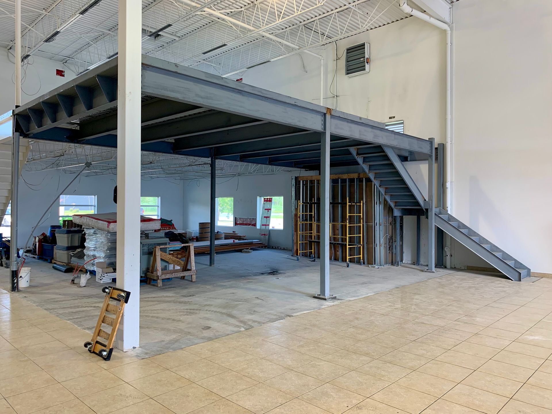 Construction d'une structure à deux étages à l'intérieur d'un grand bâtiment ; poutres d'acier, murs inachevés, escaliers.