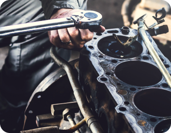 Mechanic using a wrench on an engine block.