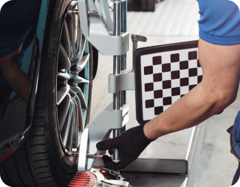 Person adjusting alignment equipment on a car wheel, using a checkerboard target.