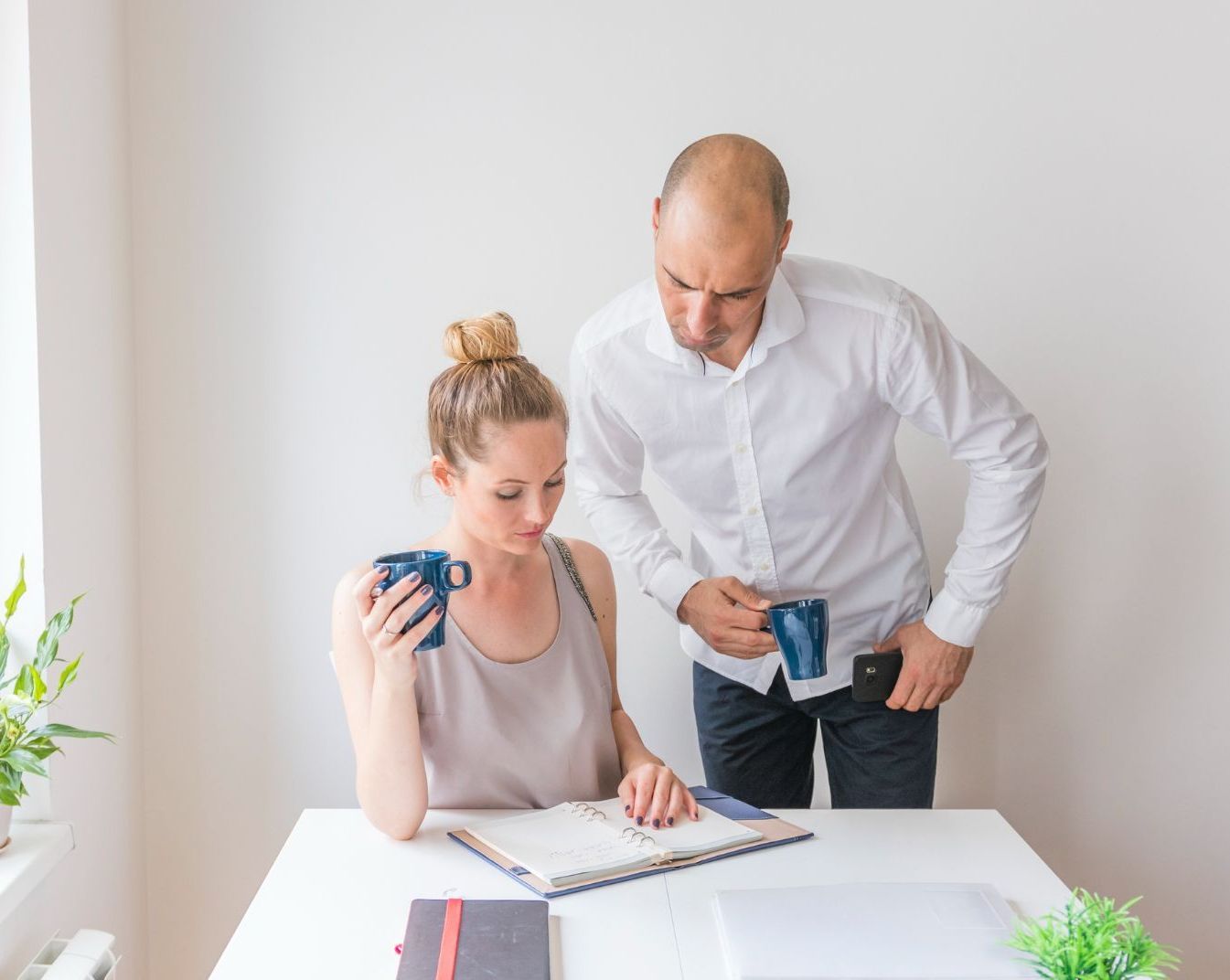 A man and a woman are sitting at a table looking at a notebook.