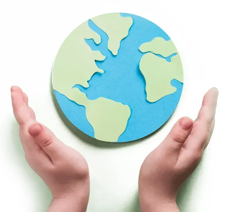 Two hands holding a paper cut out of the earth