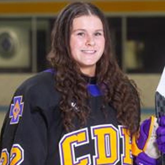 A woman in a hockey uniform is holding a hockey stick.