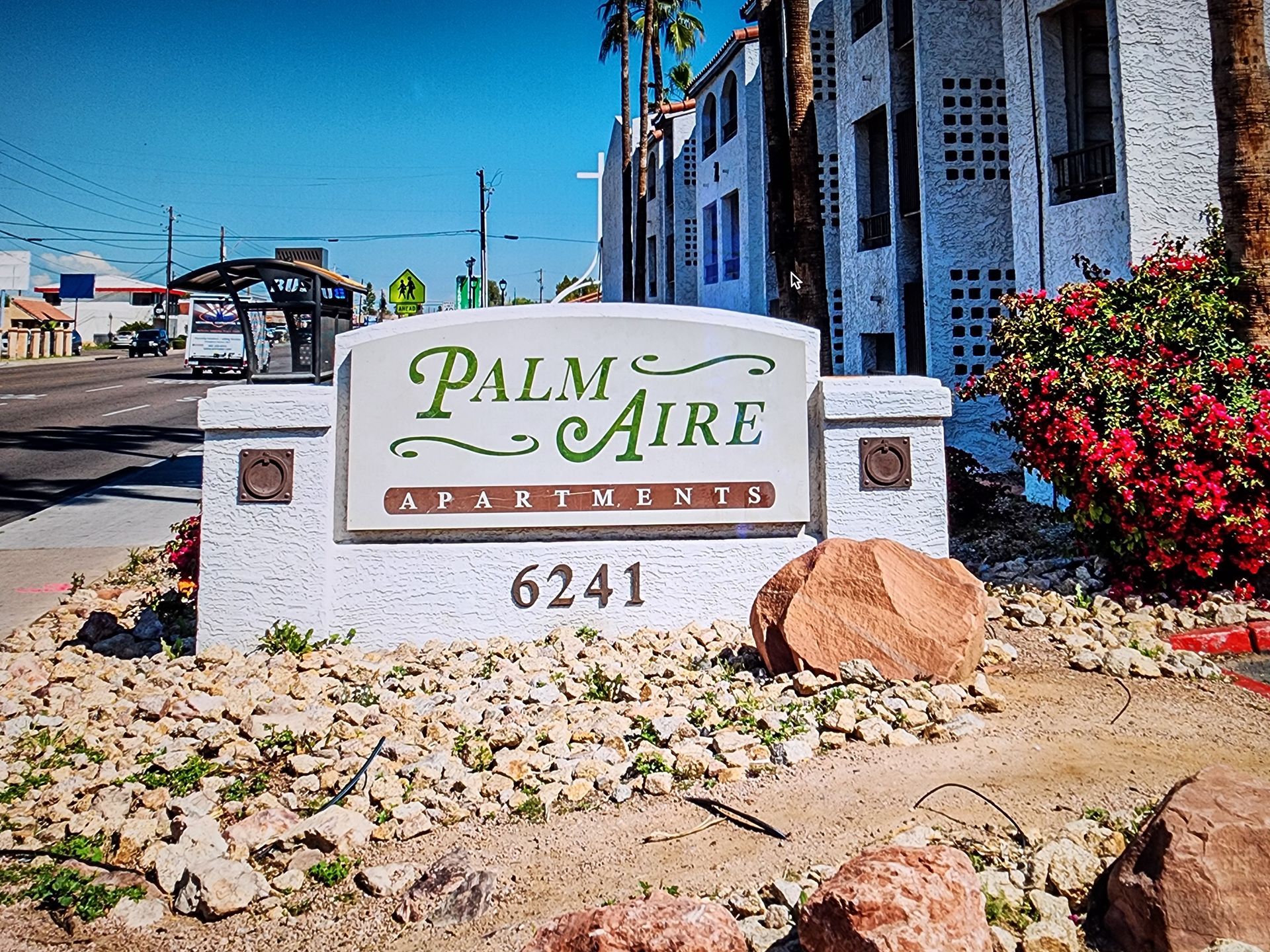 A palm aire sign is sitting in front of a building.