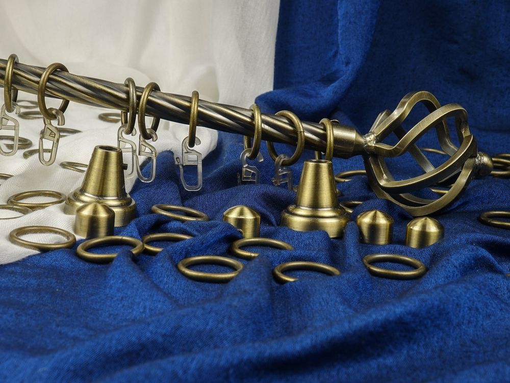 Blue fabric with brass curtain rod rings and finials laid out on a surface