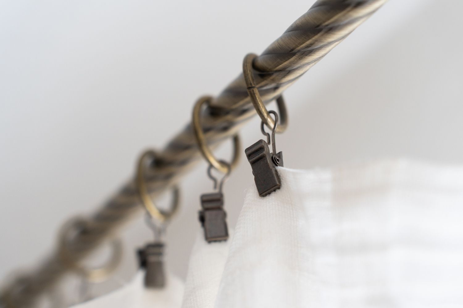 Close-up of a clothesline with metal clips hanging from a twisted cord against a white fabric backdrop