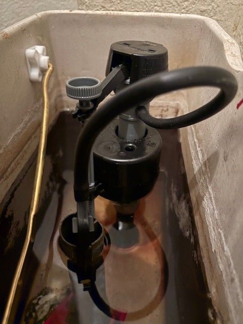 Person in red gloves inspecting pipes with a handheld device, indoors.