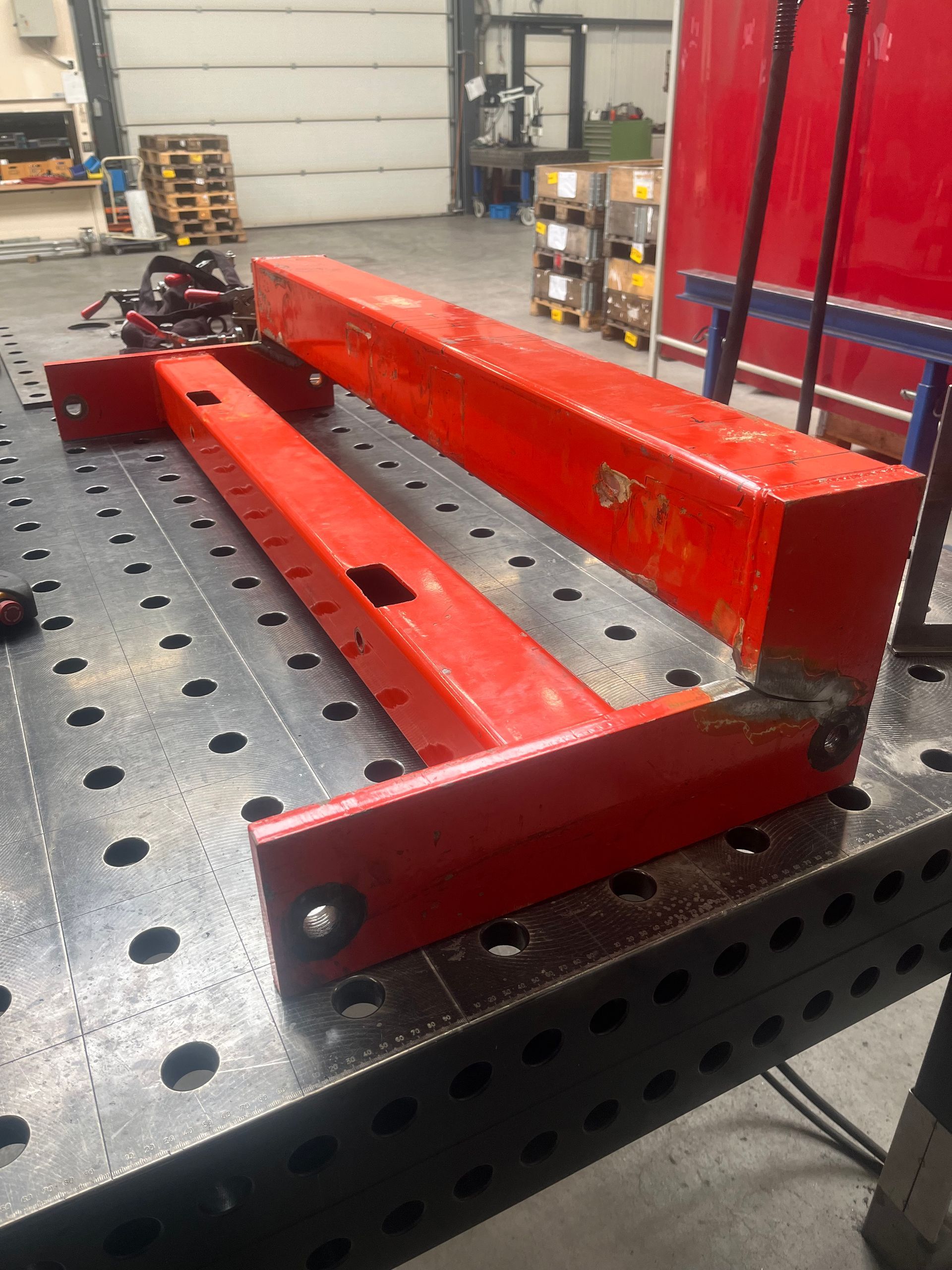 Een rood stuk metaal ligt bovenop een metalen tafel.