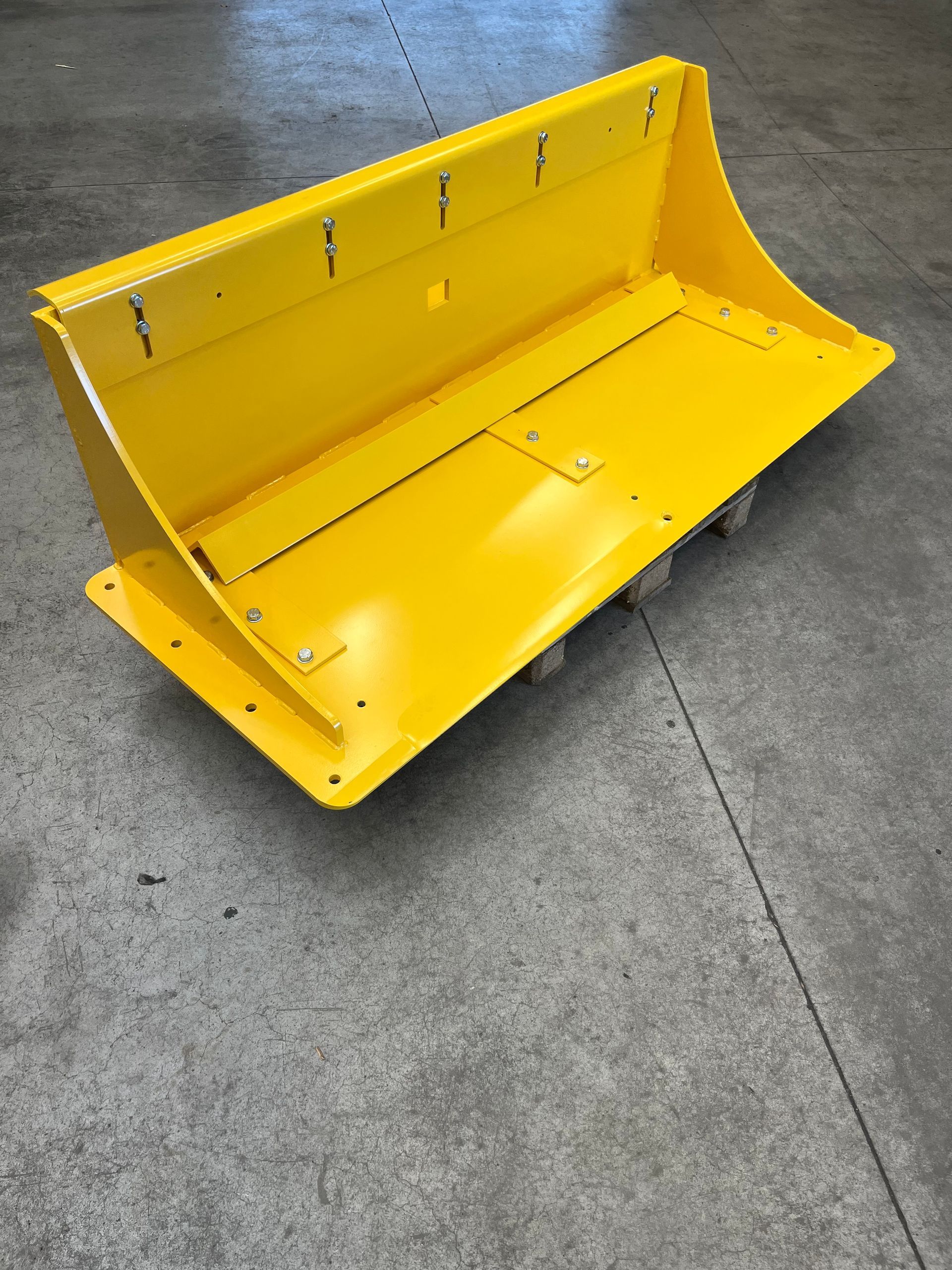 Een gele emmer staat op een betonnen vloer