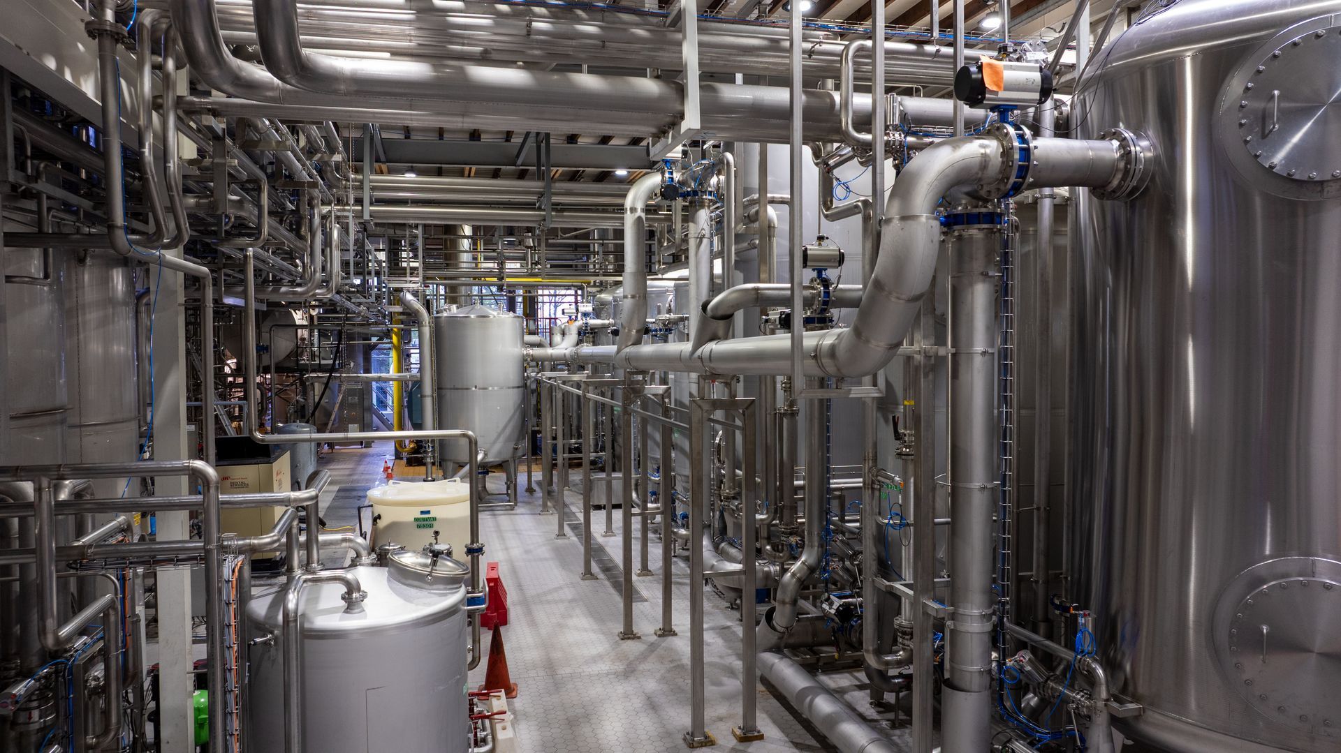 Een fabriek vol met roestvrijstalen buizen en tanks.