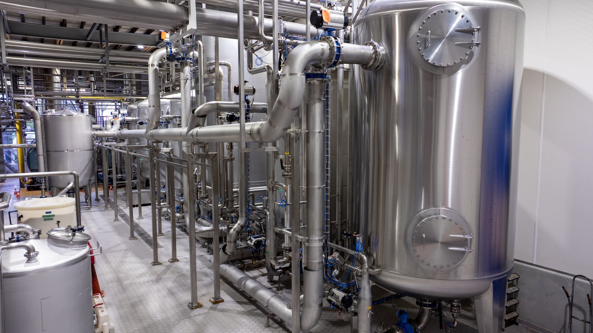 Een fabriek vol met roestvrijstalen buizen en tanks.