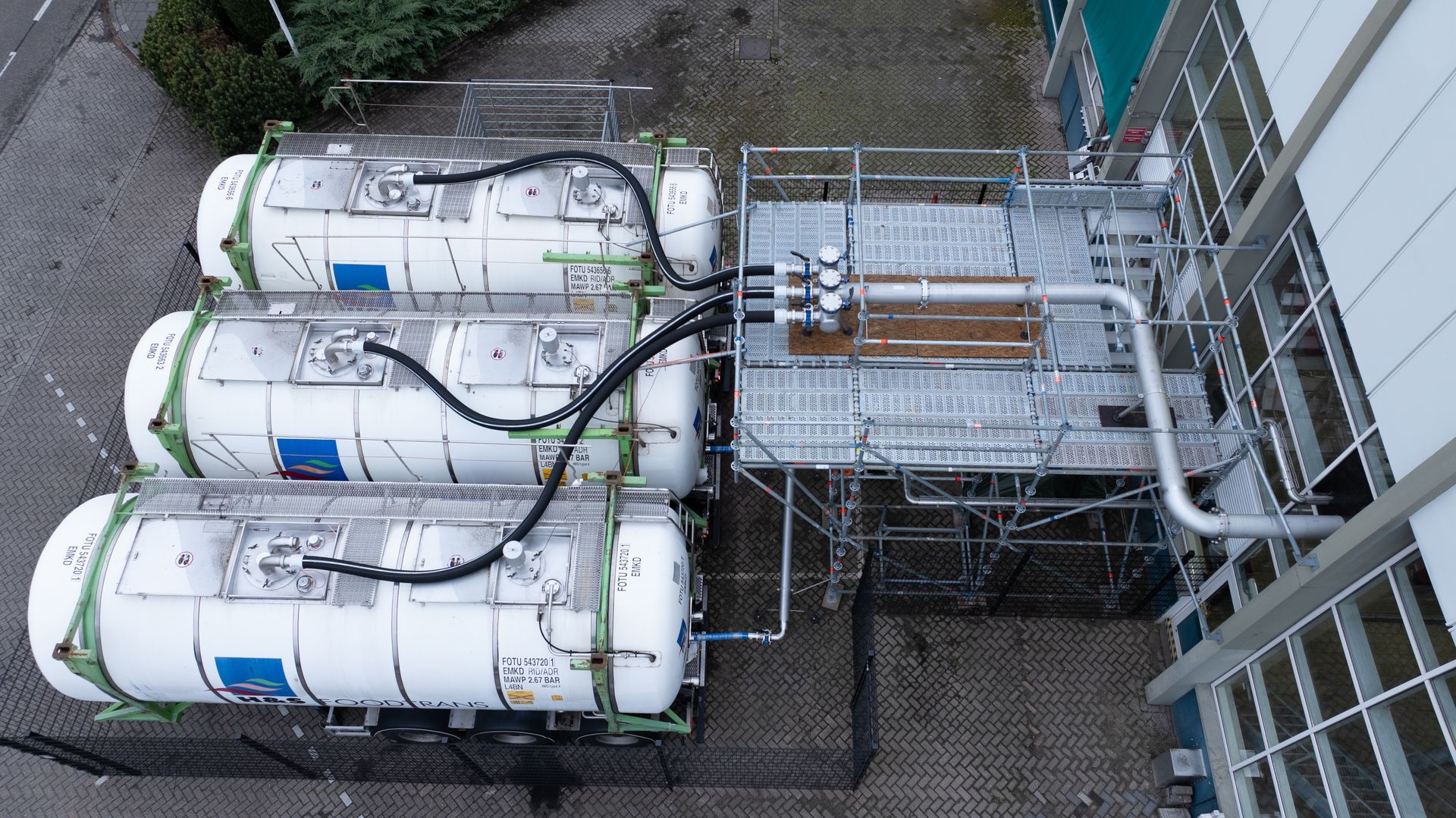 Een luchtfoto van drie tankwagens geparkeerd voor een gebouw.