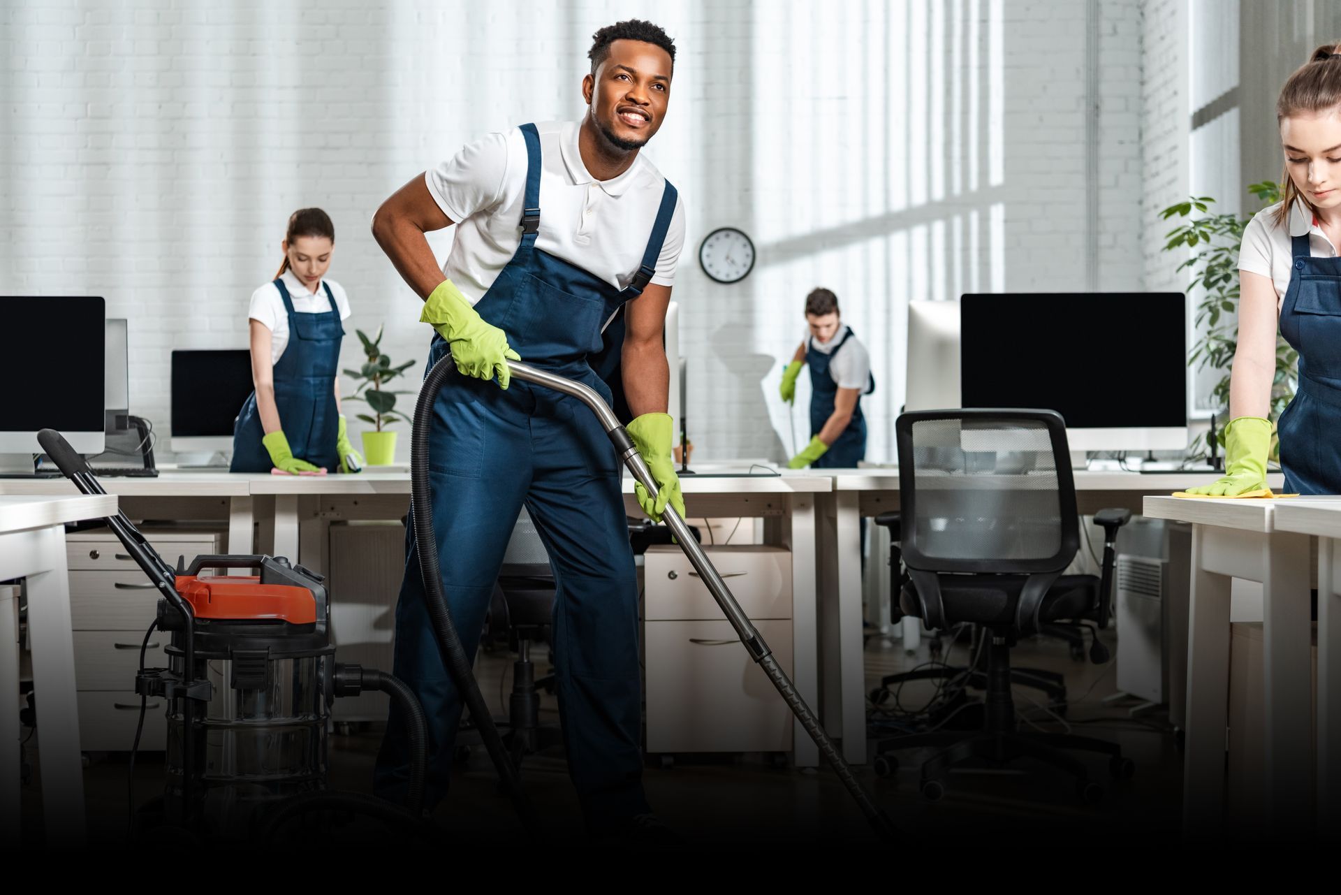A man is cleaning an office with a vacuum cleaner.