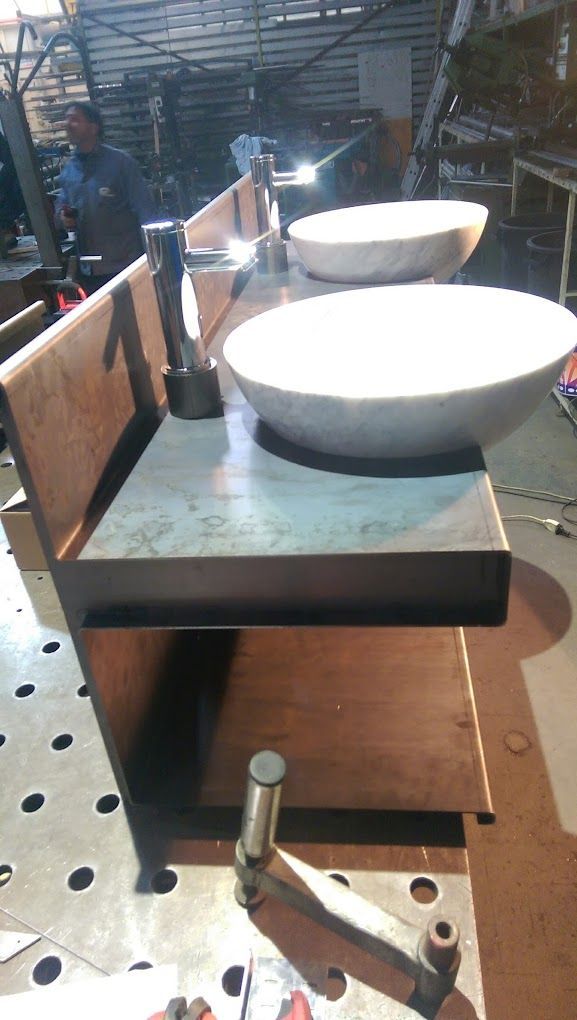 Due lavandini appoggiati su un piano di acciaio