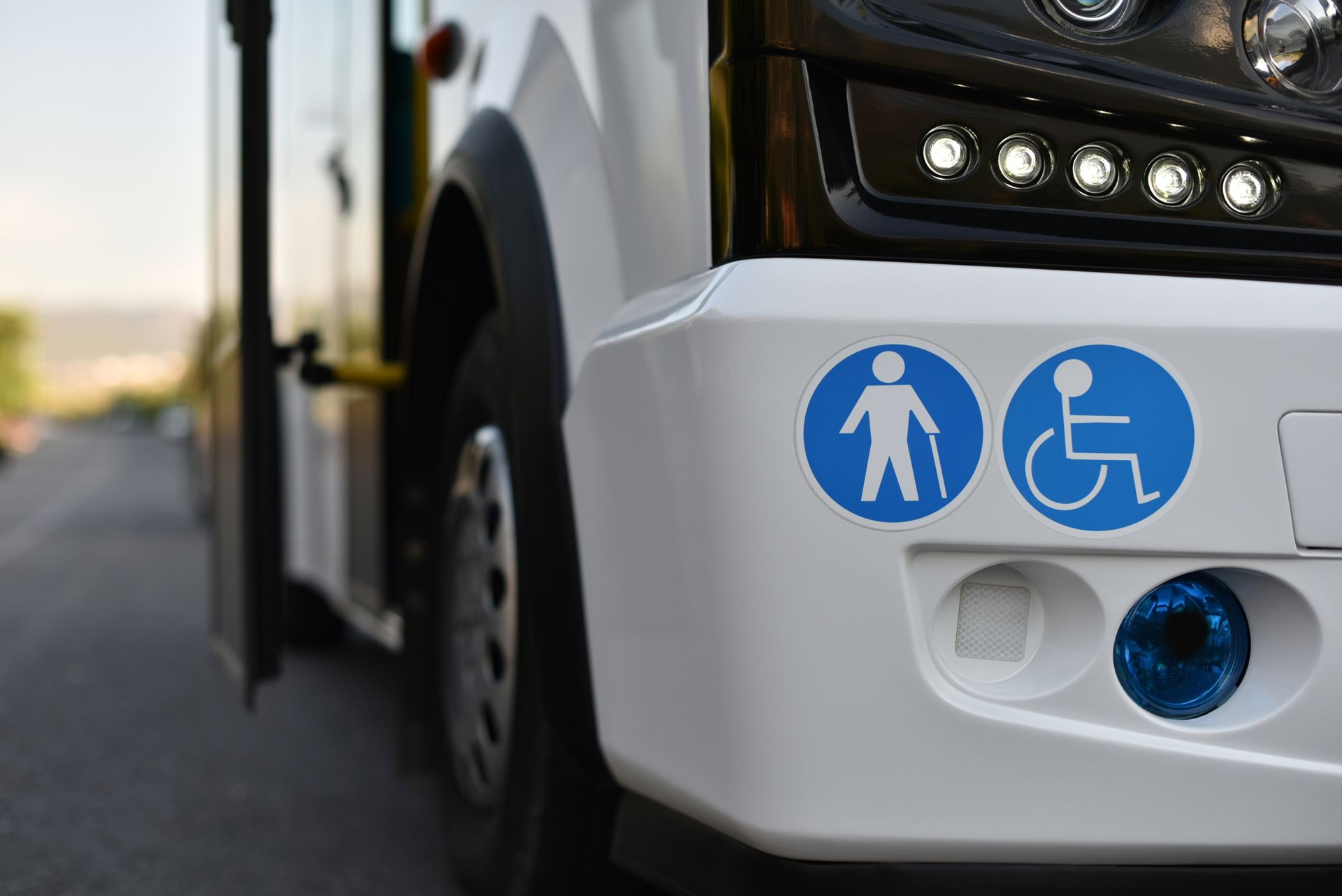 Close-up of a white bus front with accessibility and wheelchair symbols