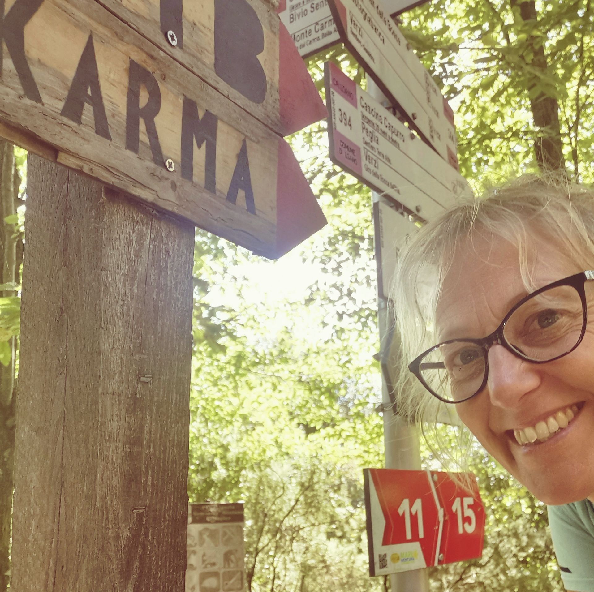 Una donna sorride vicino al cartello del sentiero con la scritta