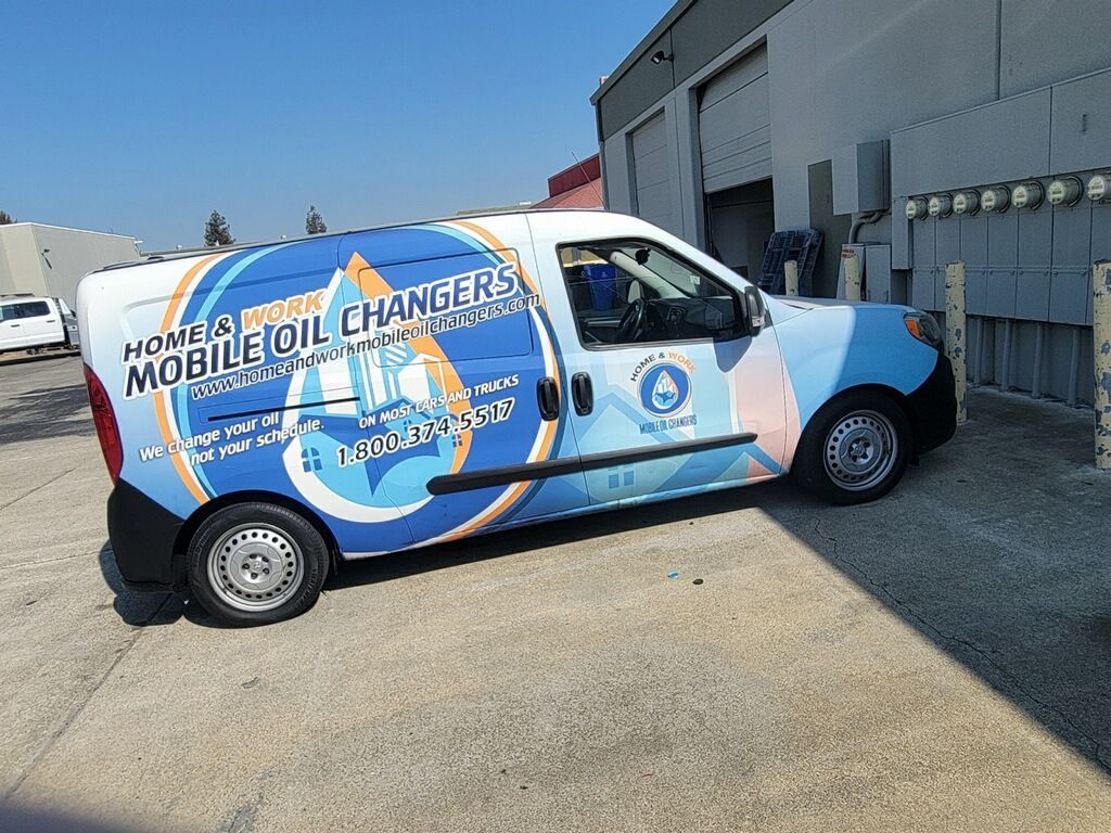 A mobile oil changers van is parked in front of a building.