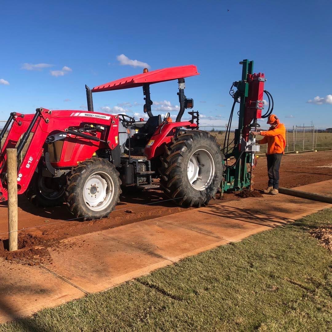 A red tractor is parked next to a green machine.