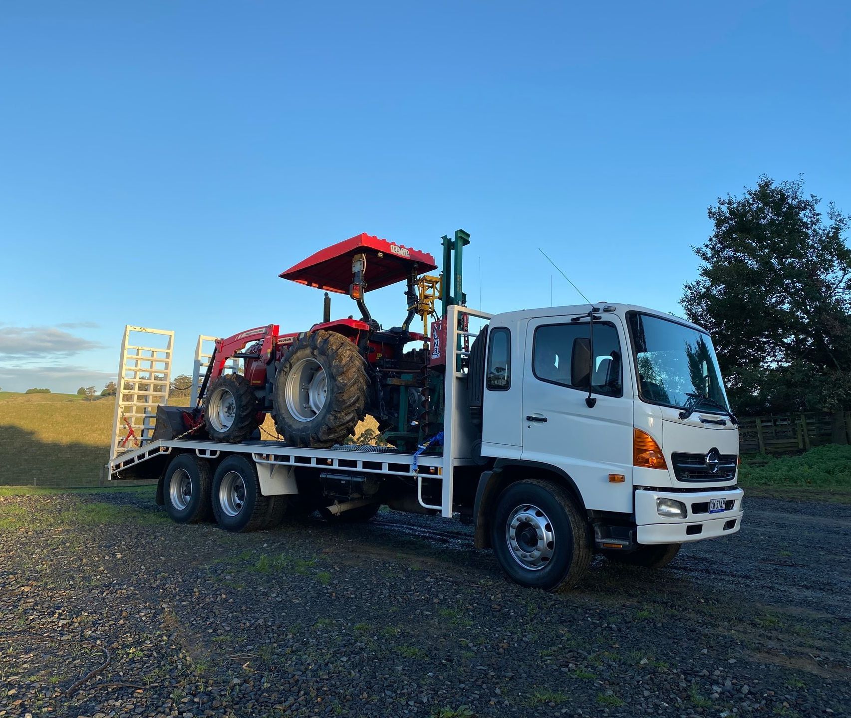 A white truck with a tractor on the back of it.