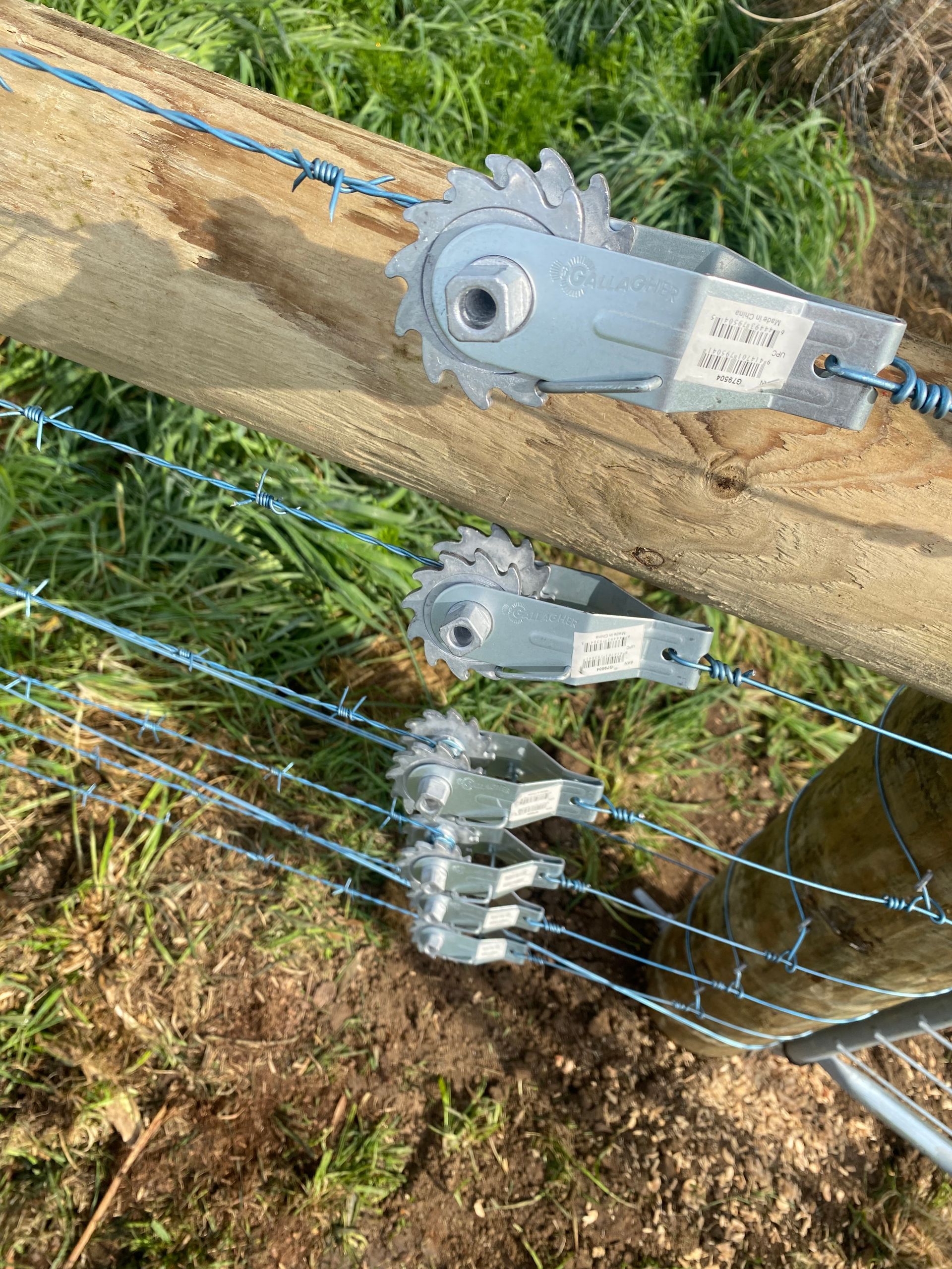 A close up of a fence with a wooden post and wire.