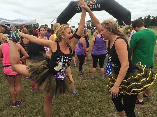 two women are giving each other a high five at a race .