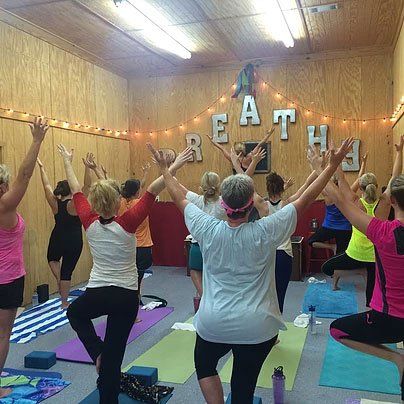 a group of women are doing yoga in a room with their arms in the air .