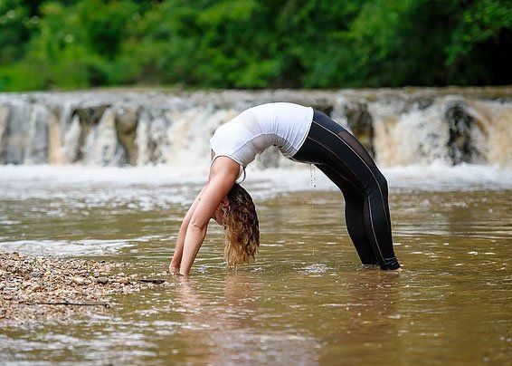 a woman is doing yoga in the water near a waterfall .