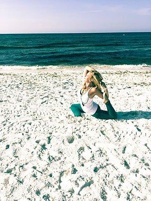 a woman is doing yoga on the beach near the ocean .