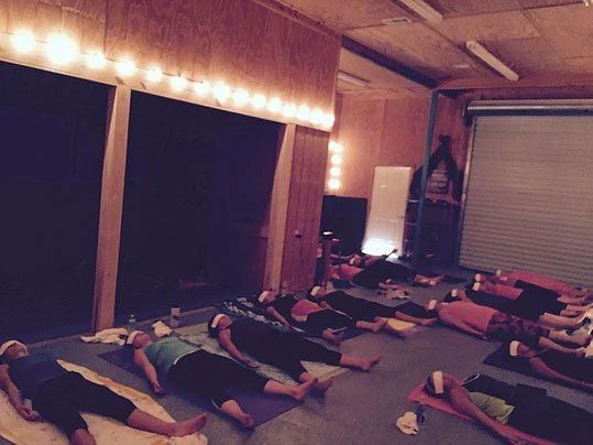 a group of people are laying on yoga mats in a room .