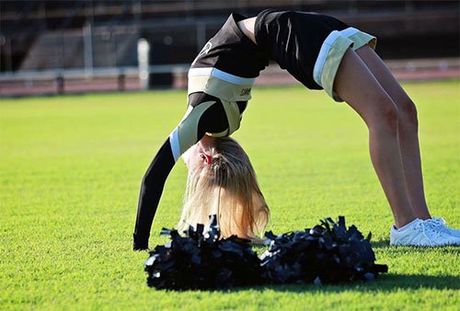 a cheerleader is doing a handstand on a field .