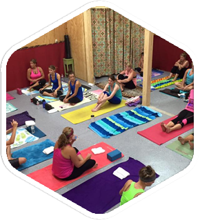 a group of women are sitting on yoga mats in a room .